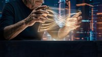Mature male professional with gray hair and beard manipulating glowing digital holographic data streams and network connections above dark surface with cityscape background.