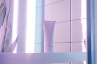 Minimalist cosmetic tube on pink background with soft window light and shadow play creating serene spa atmosphere. Modern skincare packaging concept.