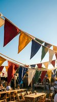 Colorful triangular bunting flags hanging outdoors at festival or market event against clear blue sky creating festive party atmosphere for celebrations.