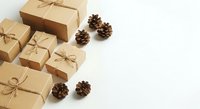 Kraft paper gift boxes tied with twine bows arranged with natural pinecones on white background for holiday packaging and seasonal decoration.