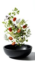 Fresh vegetables and herbs flying above black bowl on white background isolated for culinary design projects.