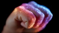 Glowing magical fist with sparkles and rainbow colors on black background, mystical energy concept showing power and strength through colorful light effects.