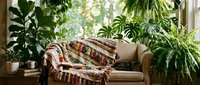 Cozy reading nook with tan leather armchair draped with woven blanket, surrounded by lush green houseplants near bright window, perfect for home decor and interior design projects.