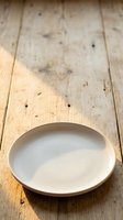 Empty white ceramic plate on rustic wooden surface with natural wear marks. Suitable for food styling, restaurant menus, and tableware design projects.