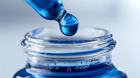 Blue liquid droplet falling from pipette into glass laboratory container, showcasing precision measurement in scientific research or cosmetic formulation.