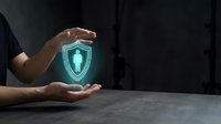 Hand holding glowing shield with cross symbol, representing digital security, data protection, and cybersecurity solutions for business and technology applications.
