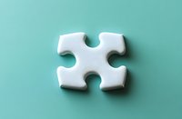 Single white puzzle piece casting soft shadow on mint green background, symbolizing solutions, teamwork and business strategy concepts.