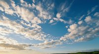 Dramatic blue sky with fluffy white clouds creating natural patterns across horizon during golden hour sunset or sunrise for backgrounds.