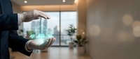 Businessman hands protecting holographic house model in modern office interior with bokeh lights representing real estate investment and property protection.