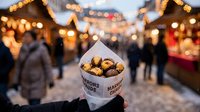 Roasted chestnuts in paper cone at festive Christmas market with warm bokeh lights and holiday atmosphere creating cozy winter evening scene.