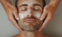 Caucasian man receiving professional facial treatment with cream mask application during spa procedure, eyes closed in relaxation, stubble beard visible.