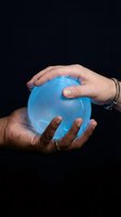 Male hands holding glowing blue crystal ball against dark background for fortune telling, mysticism, prediction and spiritual guidance concepts.
