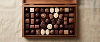 Assorted luxury chocolates in an open wooden box on a linen background, featuring dark, milk, and white pralines for gifting.