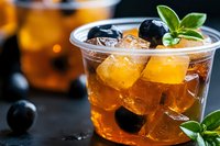 Refreshing iced tea cocktail with fresh blueberries, mint leaves and ice cubes in a clear glass, perfect for beverage menus and summer drink promotions.