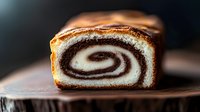 Freshly baked marble pound cake with chocolate swirl pattern shown in cross section on wooden surface, revealing soft texture and perfect spiral design. Homemade pastry.