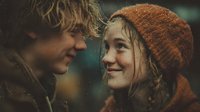 Young couple sharing intimate moment in winter, blonde man and brunette woman in knit hat looking at each other lovingly during romantic outdoor date.