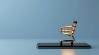 Miniature golden shopping cart placed on smartphone screen against blue background, representing mobile commerce and online shopping technology.