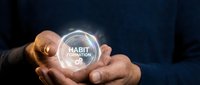 Professional businessman hands holding glowing digital sphere with habit formation text, representing personal development and behavioral change concepts.