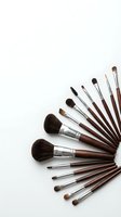 Professional makeup brush set with brown wooden handles arranged in fan pattern on white background for beauty and cosmetics applications.