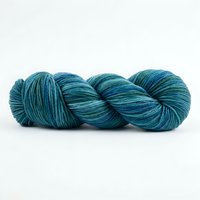 Skein of teal and blue hand-dyed yarn twisted in a coil, isolated on white background for knitting, crochet, and textile craft projects.