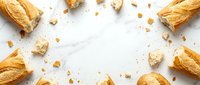 Golden croissants and pastry crumbs scattered on white marble surface, overhead flat lay composition for bakery, food styling, and culinary design projects.