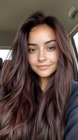 Young woman with long wavy brown hair taking selfie in car interior with natural lighting and casual style for lifestyle content.