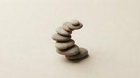 Balanced stack of smooth river stones creating zen meditation tower on neutral beige background for wellness and mindfulness concepts.