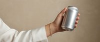 Woman hand holding blank aluminum soda can against beige background for branding mockup and product presentation design projects.