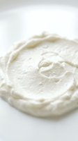 Creamy white frosting or whipped cream with soft peaks and swirls on isolated white background, ready for baking, dessert, and culinary design projects.