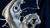 Splashing milk or cream forming abstract shapes against dark background, suitable for dairy product advertising, beverage packaging, and culinary publications.