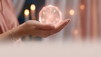 Hand holding glowing crystal sphere with geometric patterns, symbolizing future vision, technology, and innovation for business and spiritual concepts.