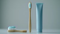 Eco-friendly bamboo toothbrushes with soft bristles and blue toothpaste tube on minimal gray background, dental care and sustainable lifestyle concept.