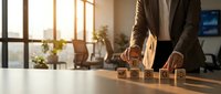 Professional businessman arranging wooden blocks with icons on office desk during golden hour sunlight, representing business strategy and planning concepts.