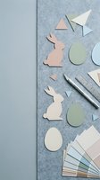 Paper craft Easter bunny cutouts with eggs and color swatches on textured surface for spring holiday DIY projects and seasonal decorating activities.