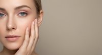 Young Caucasian woman with natural makeup touching face gently, skincare and beauty routine concept for cosmetic products and wellness advertising.