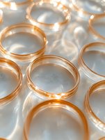 Golden wedding rings arranged on white surface with soft shadows and warm light reflections creating romantic atmosphere for jewelry photography and bridal concepts.