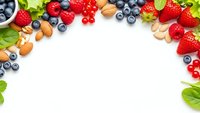 Fresh berries nuts and mint leaves frame on white background with copy space for healthy eating and nutrition concepts.