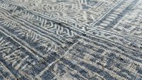Vintage woven textile with intricate geometric patterns in blue and beige tones showing detailed craftsmanship and traditional design elements.