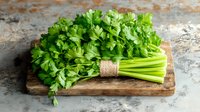 Fresh green parsley bunch tied with twine on rustic wooden cutting board against textured stone background, natural organic herbs for cooking.