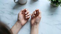 Open cupped hands reaching upward in prayer or meditation gesture on marble surface with soft natural lighting for wellness and spirituality concepts.