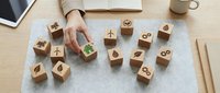 Businesswoman selecting green eco-friendly wooden cube with leaf symbol from sustainability icons on office desk for corporate responsibility planning.