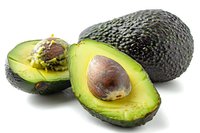 Fresh ripe avocado cut in half showing pit and creamy green flesh alongside whole dark avocado on white background, isolated food photography.