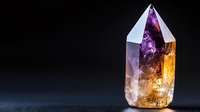 Crystal point with purple and golden hues glowing against dark background, showcasing natural mineral formation with ethereal light and mystical energy for spiritual decor.