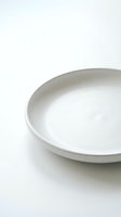 Empty white ceramic plate on clean white background for minimalist kitchen and dining design concepts.