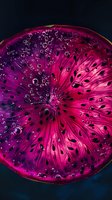 Vibrant pink and purple citrus slice with water droplets and seeds against dark background, macro photography showing detailed texture and translucent flesh.