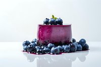 Elegant purple berry panna cotta dessert with fresh blueberries on white background, showcasing gourmet culinary creation for restaurant menu photography.