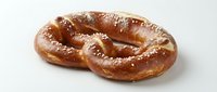 Freshly baked pretzel with golden-brown crust and coarse salt crystals on white background, isolated for bakery, food packaging, and menu design use.