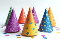 Colorful party hats with stars and dots pattern on white background with scattered confetti stars. Festive birthday celebration accessories for holiday events.