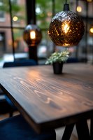 Modern restaurant interior with textured glass pendant lamp hanging over wooden table, creating warm ambient lighting and cozy atmosphere for dining space.