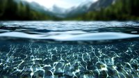 Split view of crystal clear mountain lake water showing underwater light patterns with snow-capped peaks and pine forest in background, nature photography.